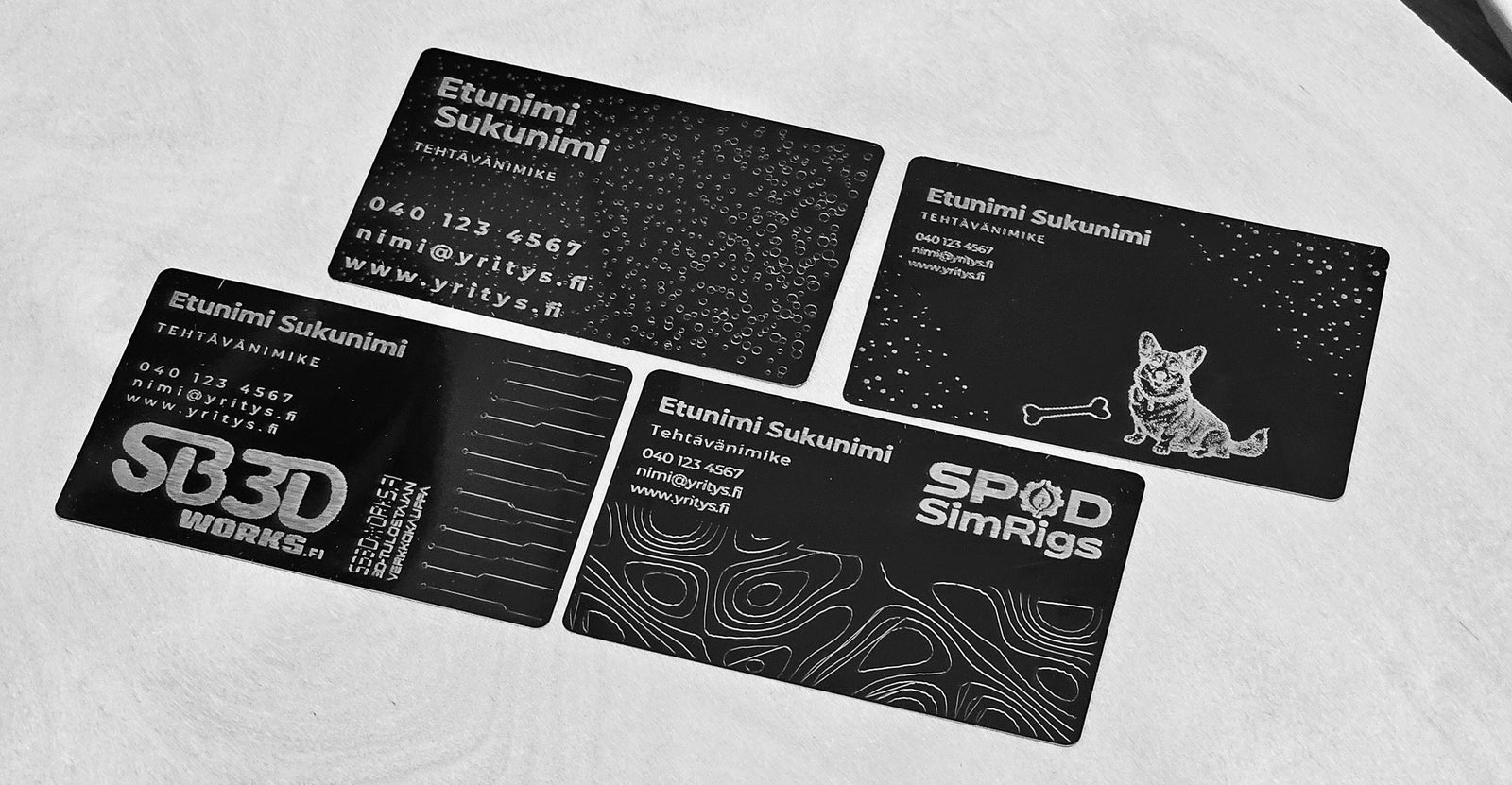 Neljä laserkaiverrettua käyntikorttia mustasta anodisoidusta alumiinista